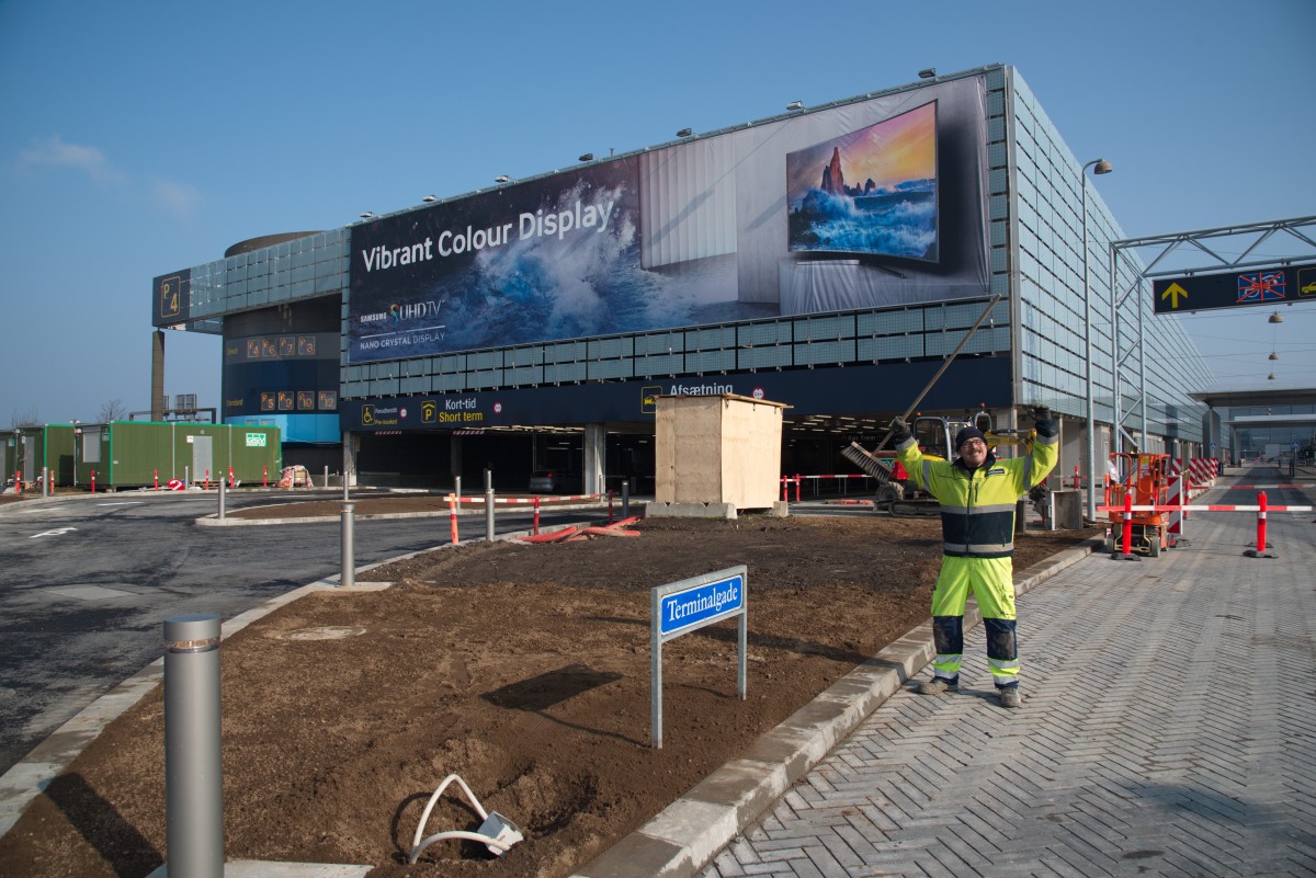 En glad medarbejder ved Københavns Lufthavn byder velkommen til det nyåbnede "Kiss & Fly" anlæg i parkeringshuset P4.